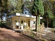 A detached bungalow with outdoor fireplace, covered terrace and pond in a forest plot