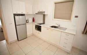 a kitchen with white cabinets and white appliances, Alivio Tourist Park Canberra in Canberra