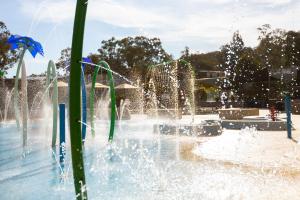 a water fountain with people swimming in it, Alivio Tourist Park Canberra in Canberra