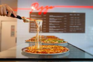 a person pouring a glass of wine into a pizza, Alivio Tourist Park Canberra in Canberra
