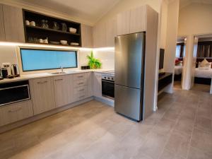 a kitchen with a refrigerator, sink, and microwave, Alivio Tourist Park Canberra in Canberra