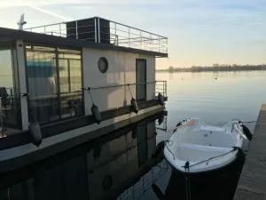 Modernes festliegendes Hausboot mit großzügiger Dachterrasse und Ruderboot - Ludorf
