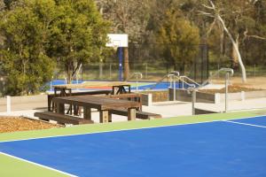 a tennis court with a bench and a tennis racket, Alivio Tourist Park Canberra in Canberra