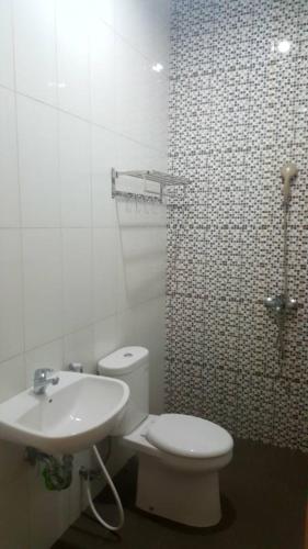 a white toilet sitting next to a white sink, Hotel Amalia Malioboro in Yogyakarta