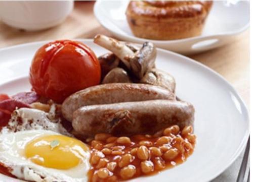 a white plate topped with eggs, sausage and bacon, The Ayrshire and Galloway in Ayr