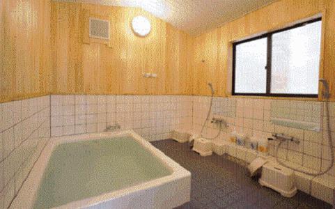 a bath tub sitting next to a toilet in a bathroom, Cottage Inn Log-cabin in Karuizawa