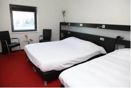 a hotel room with two beds and a television, Stads Hotel Boerland in Emmen