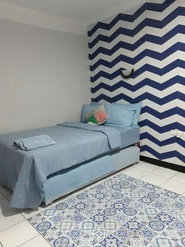 a bedroom with a blue and white striped bedspread, Cihampelas Homestay in Bandung