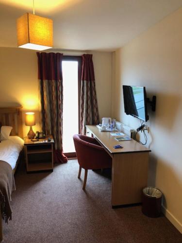 a bedroom with a bed, desk and television, The Brae Hotel in Brae