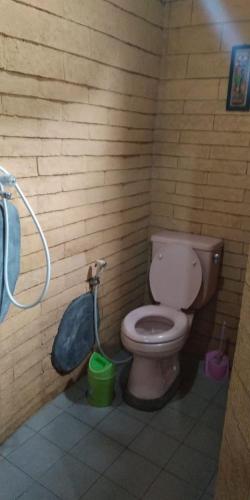 a bathroom with a toilet and a trash can, Enny's Guest House in Malang