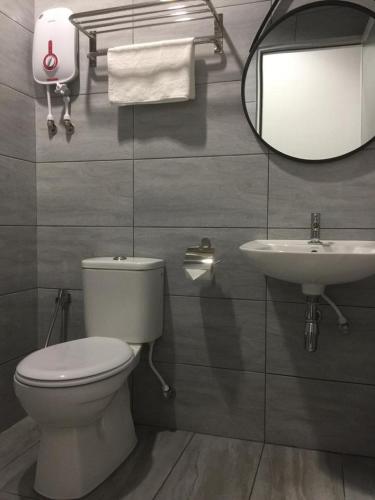 a bathroom with a toilet, sink and mirror, Urban Inn Alor Setar in Alor Setar