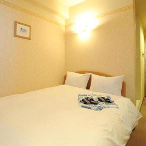 a bed with a white comforter and pillows, Hotel Benex Yonezawa in Yonezawa
