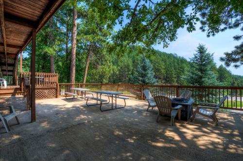 Spacious outdoor patio at Powder House Lodge in Keystone, South Dakota, with picnic tables and Adirondack chairs surrounded by tall pine trees and forest views.