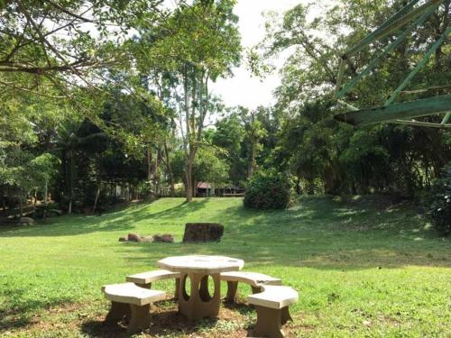 a wooden bench sitting in the middle of a grassy field, คุ้งน้ำ รีสอร์ท นครนายก in Nakhon Nayok