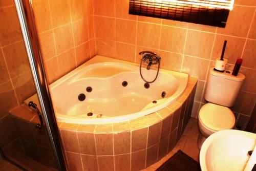 a bath tub sitting next to a toilet in a bathroom, Flintstones Guest House Durban in Durban