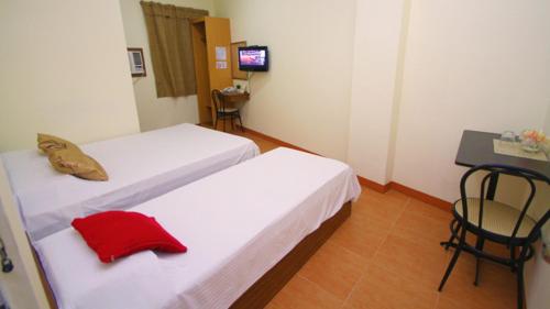 a hotel room with two beds and a television, Robe's Pension House in Cebu