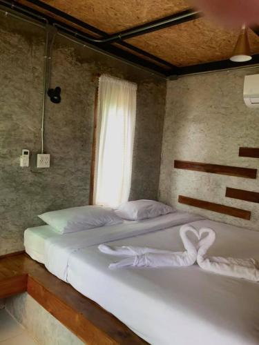 a bedroom with a white bed and white walls, The Nanda Resort in Phrae