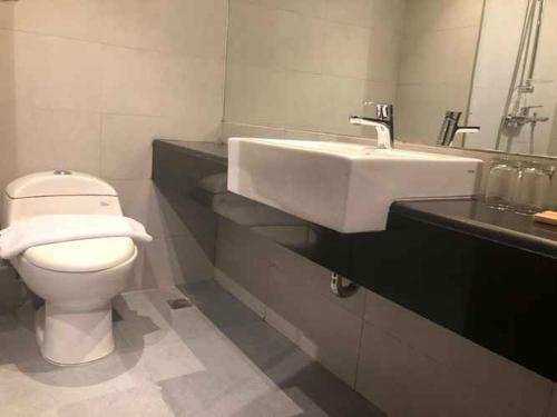 a white toilet sitting next to a sink in a bathroom, Mahkota Hotel Singkawang - CHSE Certified in Singkawang
