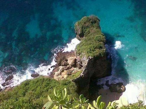 a large body of water with a bunch of rocks, Made Roejas Family in Bali