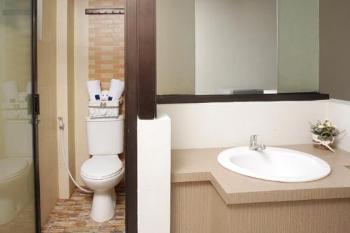 a bathroom with a toilet, sink and mirror, D'Paragon Manduro in Surakarta