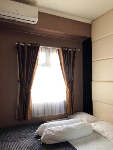 a bedroom with a bed and a window, 2BR Green Pramuka Apartment in Jakarta