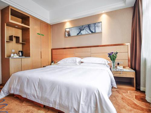 a hotel room with a bed and a dresser, Vienna International Hotel Wuhan Jiedaokou Branch in Wuhan