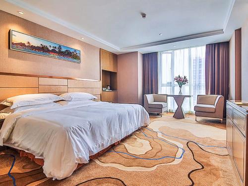 a hotel room with a bed, chair, desk and a television, Vienna International Hotel Wuhan Jiedaokou Branch in Wuhan