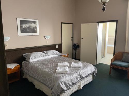 a bedroom with a bed and a dresser, Grand Hotel - Whangarei in Whangarei