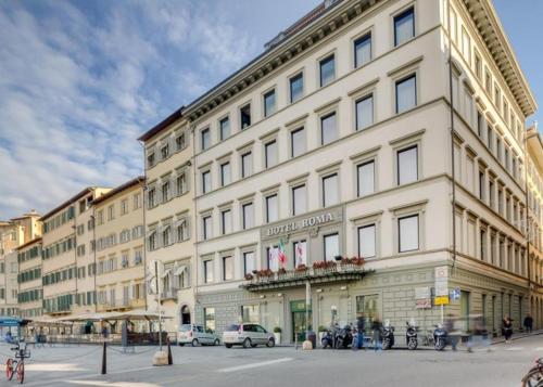 a large building with a clock on the side of it, Hotel Roma in Florence
