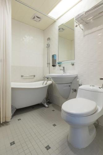 a white toilet sitting next to a bath tub in a bathroom, Just Enjoy Business Hotel in Tainan