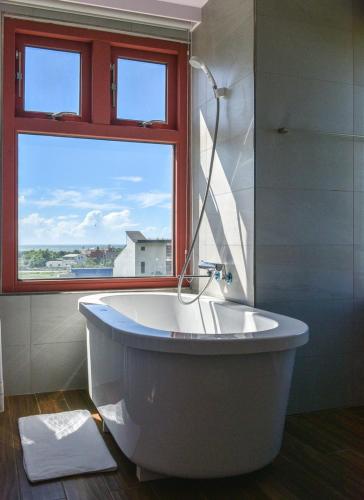 a bath tub sitting next to a window in a bathroom, First Shanhai Hotel in Yilan