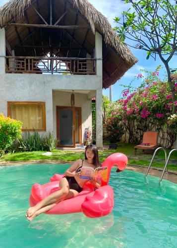a woman sitting on a red chair in a swimming pool, Lang Ca Voi (The Whales Village) Guesthouse in Phan Thiet