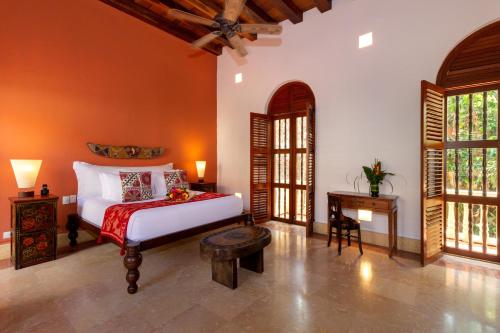 room with a wooden bed an furniture and large windows at a small luxury hotel Cartagena
