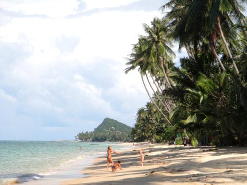 a beach scene with a couple of people on the beach, Bangpo Village in Koh Samui