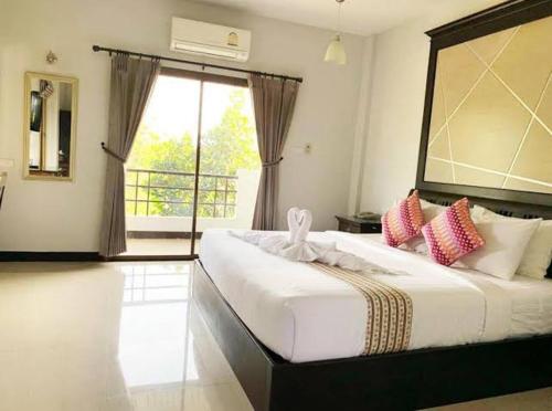 a white bed sitting in a bedroom next to a window, Rittiboon Vintage Hotel in Phrae