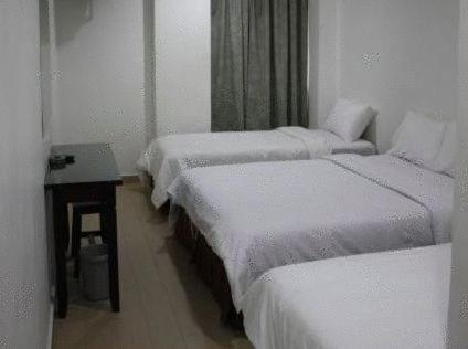 a hotel room with two beds and a desk, Dynasty Inn Wakaf Che Yeh in Kota Bharu