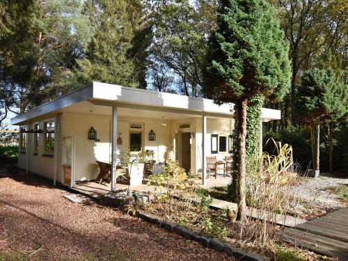A detached bungalow with outdoor fireplace covered terrace and pond in a forest plot
