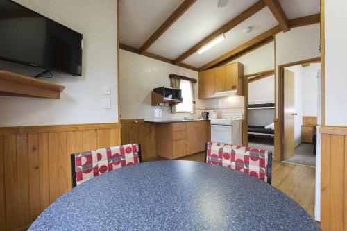 a kitchen with a table, chairs and a microwave, Alivio Tourist Park Canberra in Canberra