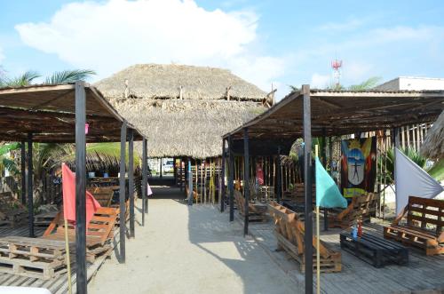 Photo of covered seating areas on the beach in front of a larger thatched roof structure