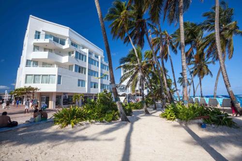 View of a white San Andres Resort through palm trees from the beach