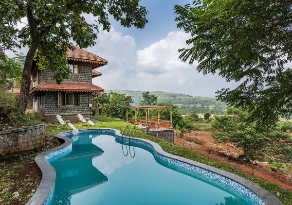 The photo shows the SaffronStays Niramay - 3BR Velhe villa, infinity pool, organic farm, library, valley & forest views near Torna-Rajgad located in the city of Mārg Āsni.