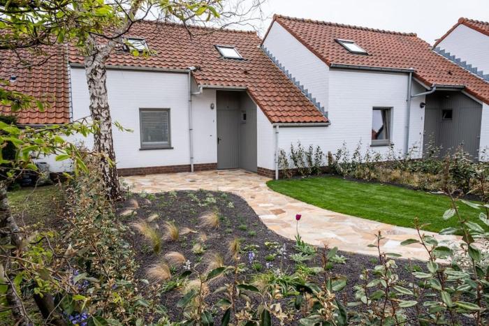 A little white house with a tree by the sea with beach cabin by BLOSS