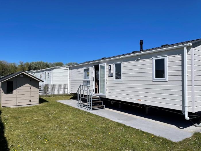Modern caravan on small campsite near woods & sea
