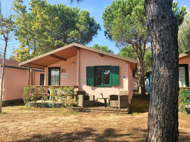 Holzchalet mit überdachter Veranda und Terrassenmöbeln auf einem schönen Campingplatz Images