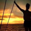 a woman standing on a boat at sunset