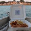 a lunch box with fish and a drink on a boat