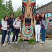 a group of people standing next to a totem pole