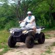 a man sitting on a four wheeler on a dirt road