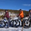 a group of three people on bikes in the snow
