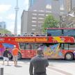 a red double decker bus with people standing in front of it